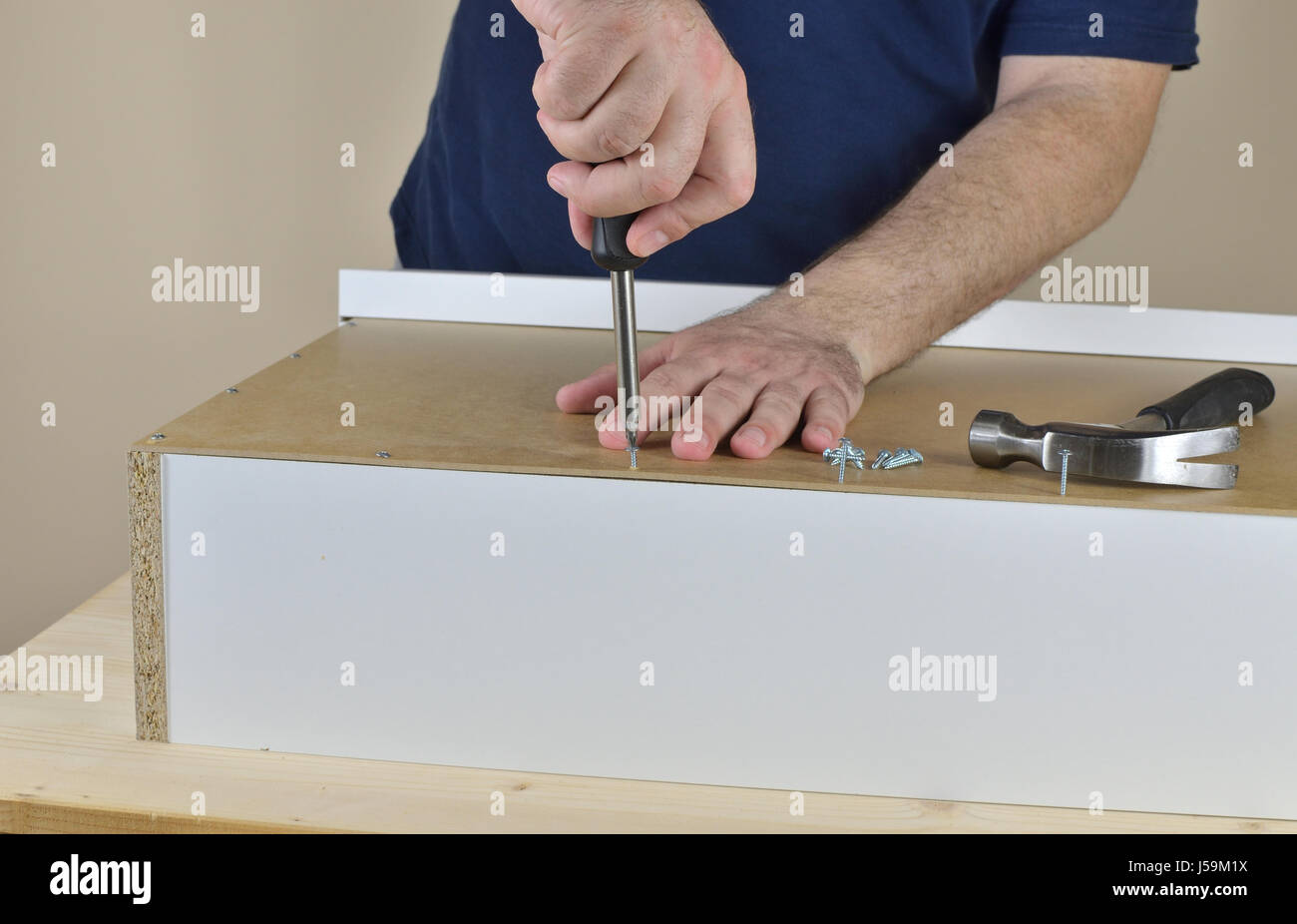 Mani dell'uomo avvitando una vite per legno in un cassetto retro impostata sul tavolo di lavoro Foto Stock
