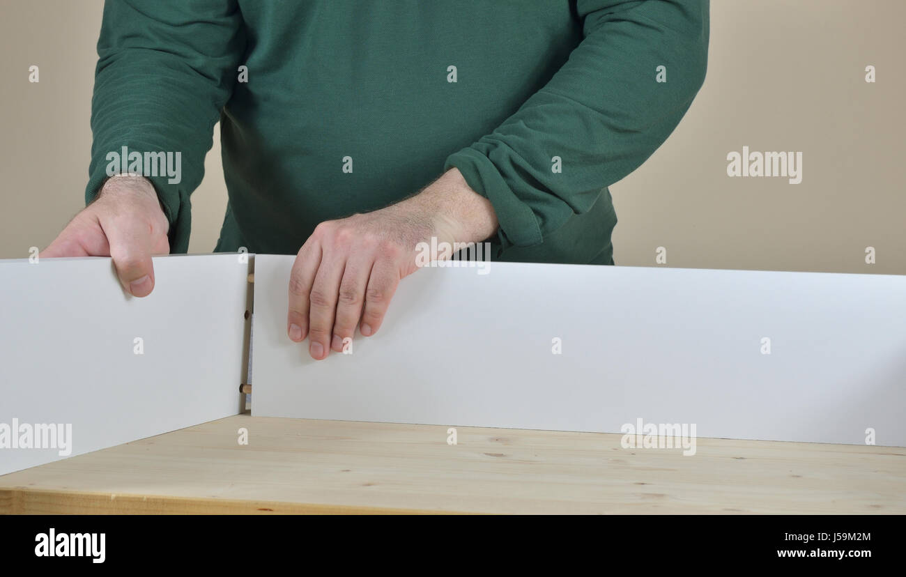 L'uomo il fissaggio di due lati di un cassetto impostato sul tavolo di lavoro Foto Stock