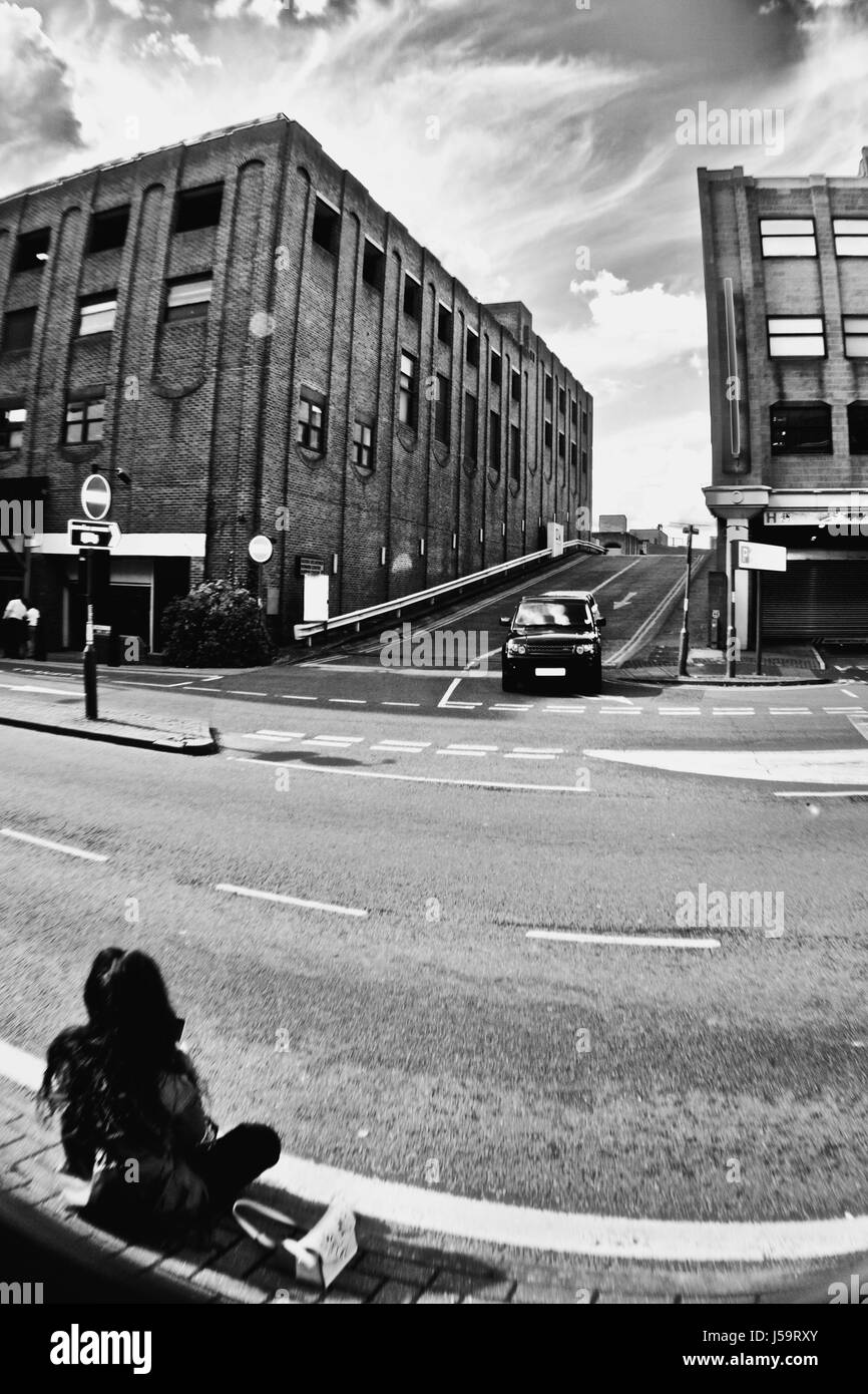 Ragazza seduta sul pavimento in Bedford Centro Città Foto Stock