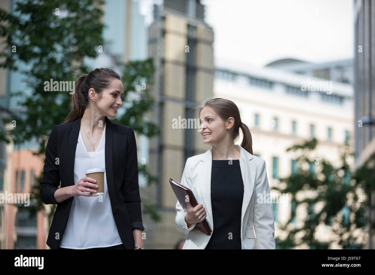 Ritratto di due business caucasica donne parlare fuori ufficio moderno edifico. Foto Stock