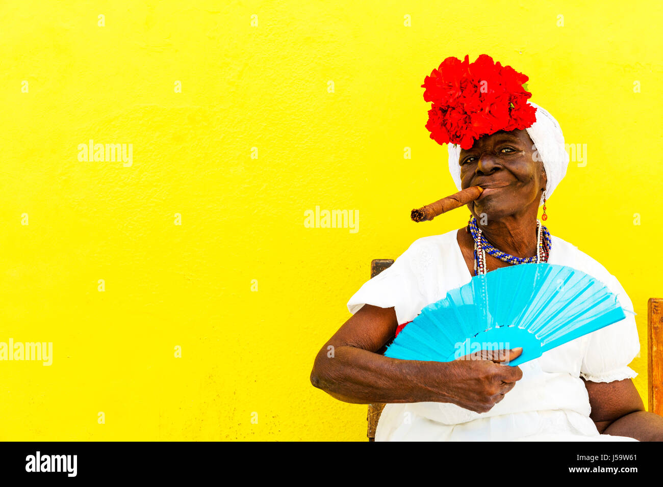 Donna cubana con sigaro in bocca in posa per i turisti a guadagnare denaro per le foto Cuba Havana donna sigaro in posa con ventola Caraibi donna Foto Stock