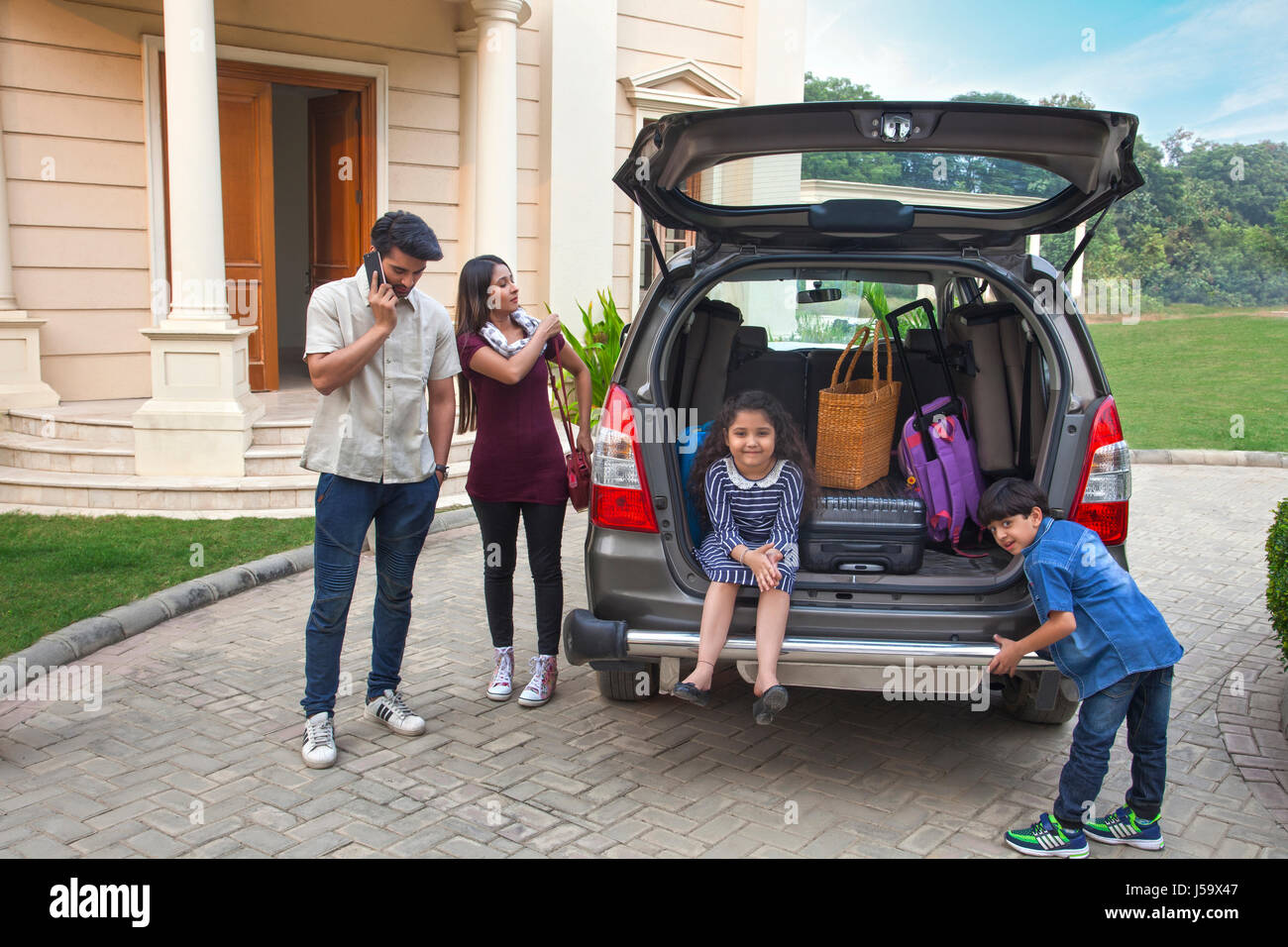 Famiglia in piedi vicino alla macchina per andare in vacanza Foto Stock