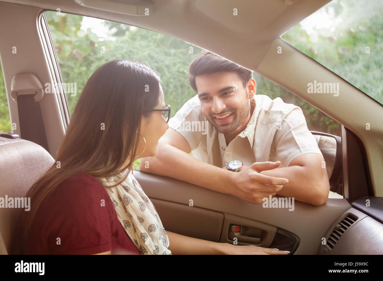 Uomo appoggiato sulla finestra auto parlando di donna Foto Stock