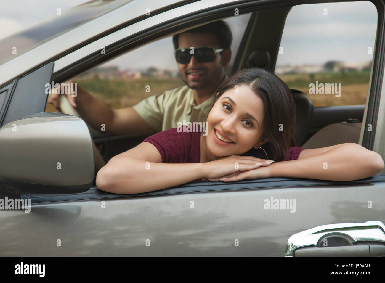 Giovane donna rilassante sulla portiera della macchina durante il viaggio in macchina Foto Stock