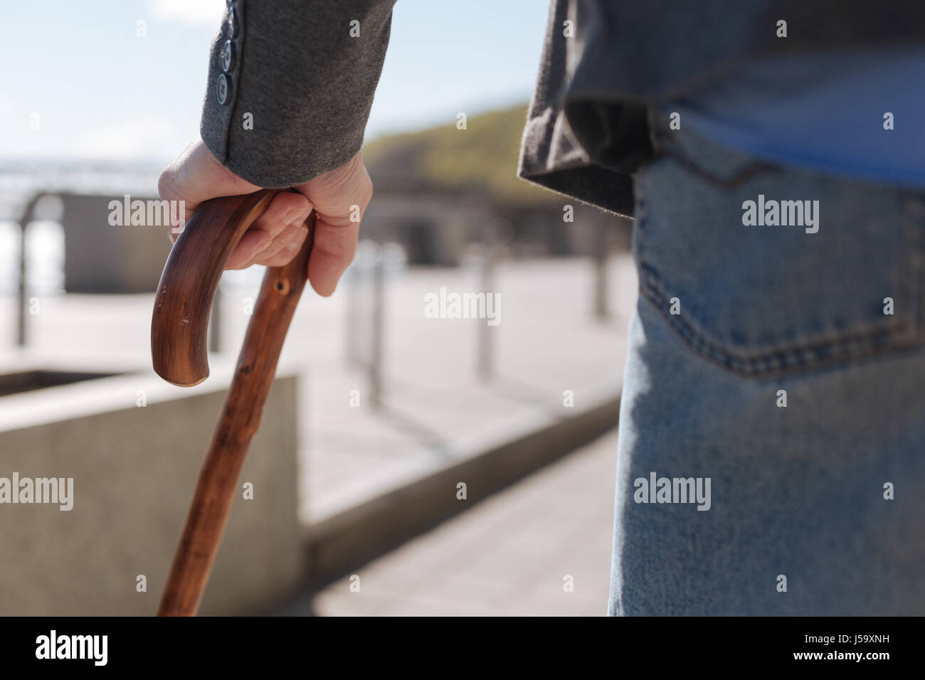 Uomo malato di trattenimento contro stick in strada Foto Stock