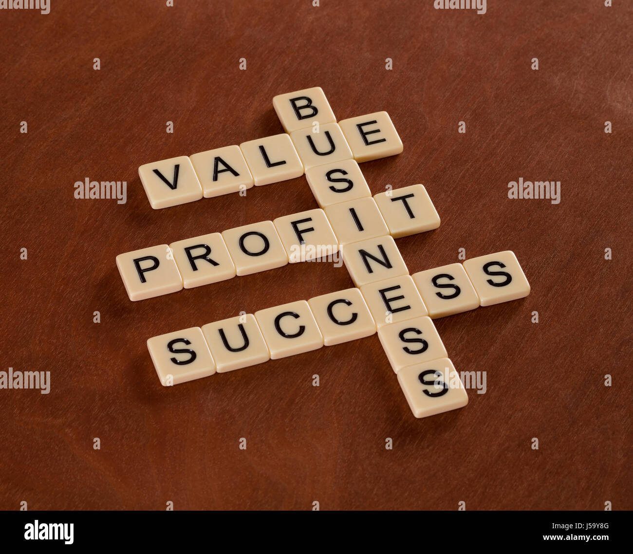 Cruciverba con parole valore, profitti aziendali. Successo nel Business del concetto. Piastrelle color avorio con lettere maiuscole sulla scheda di mogano. Foto Stock