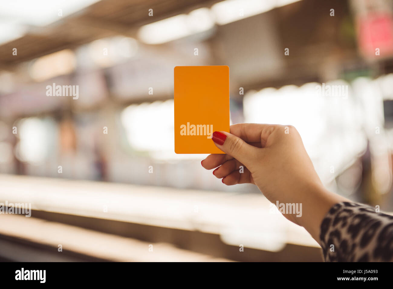 Donna mano azienda smartcard per mrt o treno su sfocati della stazione ferroviaria Foto Stock