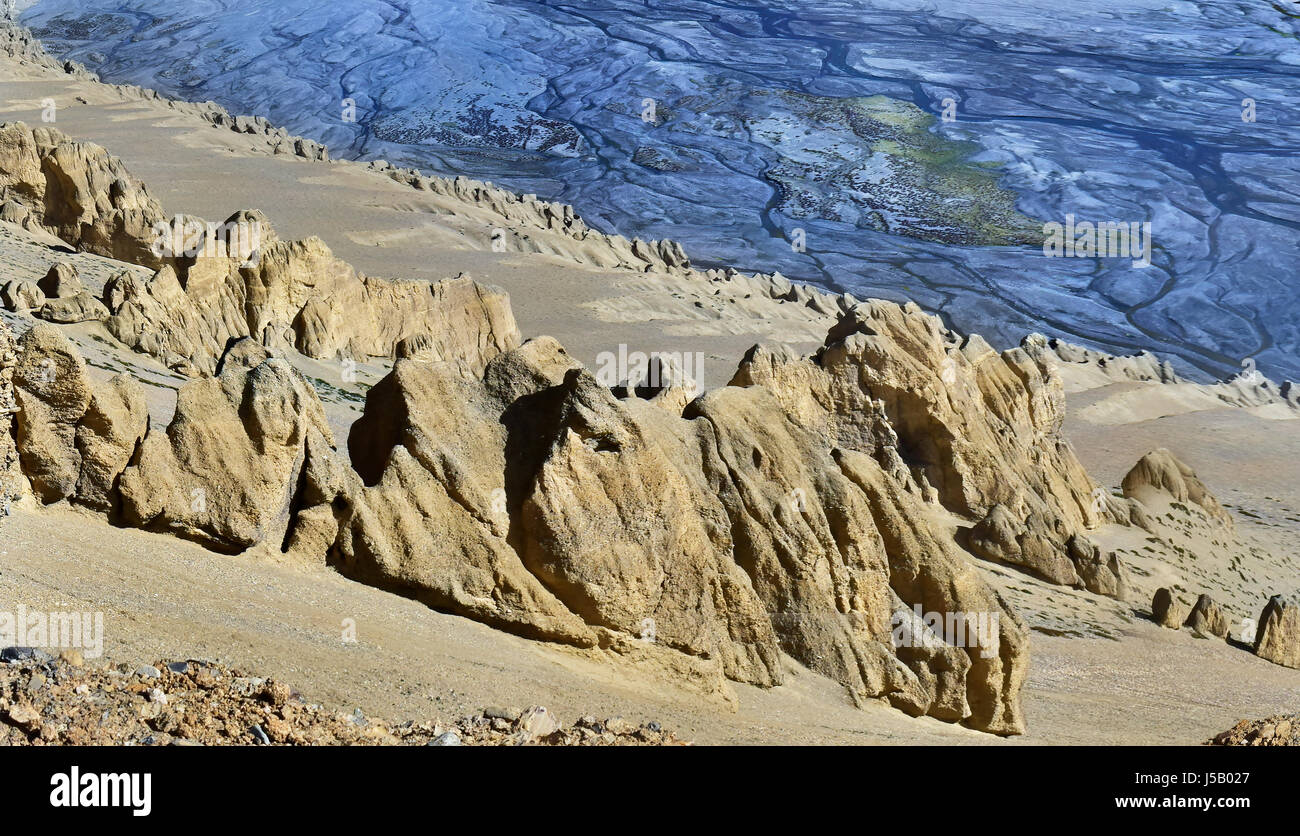 Canyon in alta montagna: alla ribalta il giallo di montagna di sabbia con la pietra di idoli e dietro il blu riverbed con numerosi torrenti, Tibet, India. Foto Stock