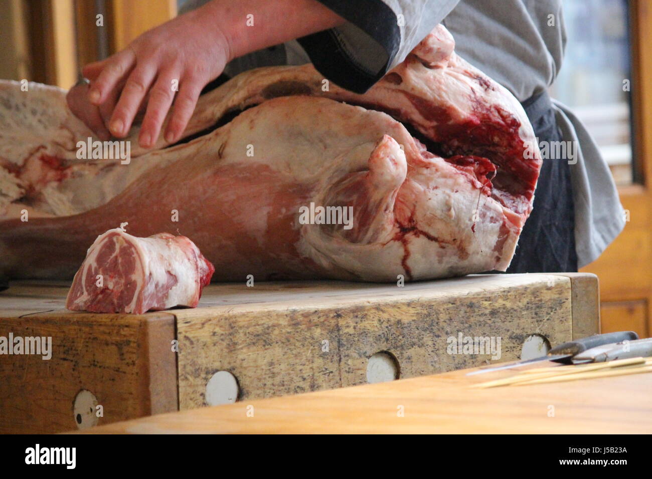 Butcher il taglio di una carcassa di agnello su un blocco di Macellai Foto Stock
