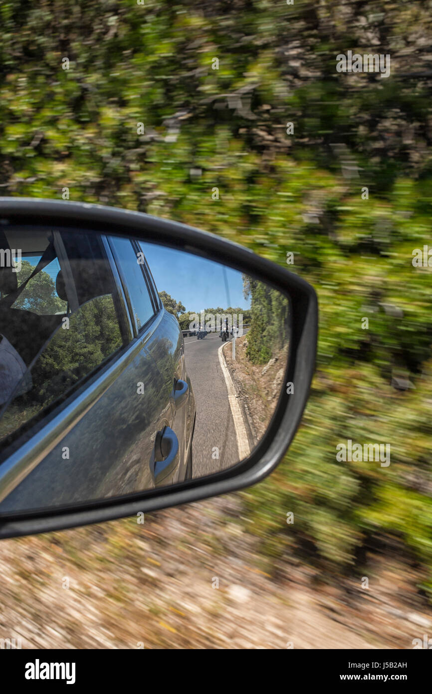 Moto sulla strada di avvicinamento auto come si vede nella parte posteriore dello specchietto retrovisore Foto Stock