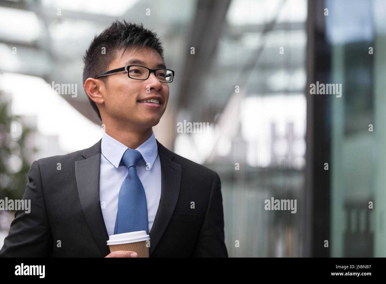 Ritratto di un imprenditore cinese al di fuori ufficio moderno edificio, guardando lontano. Foto Stock
