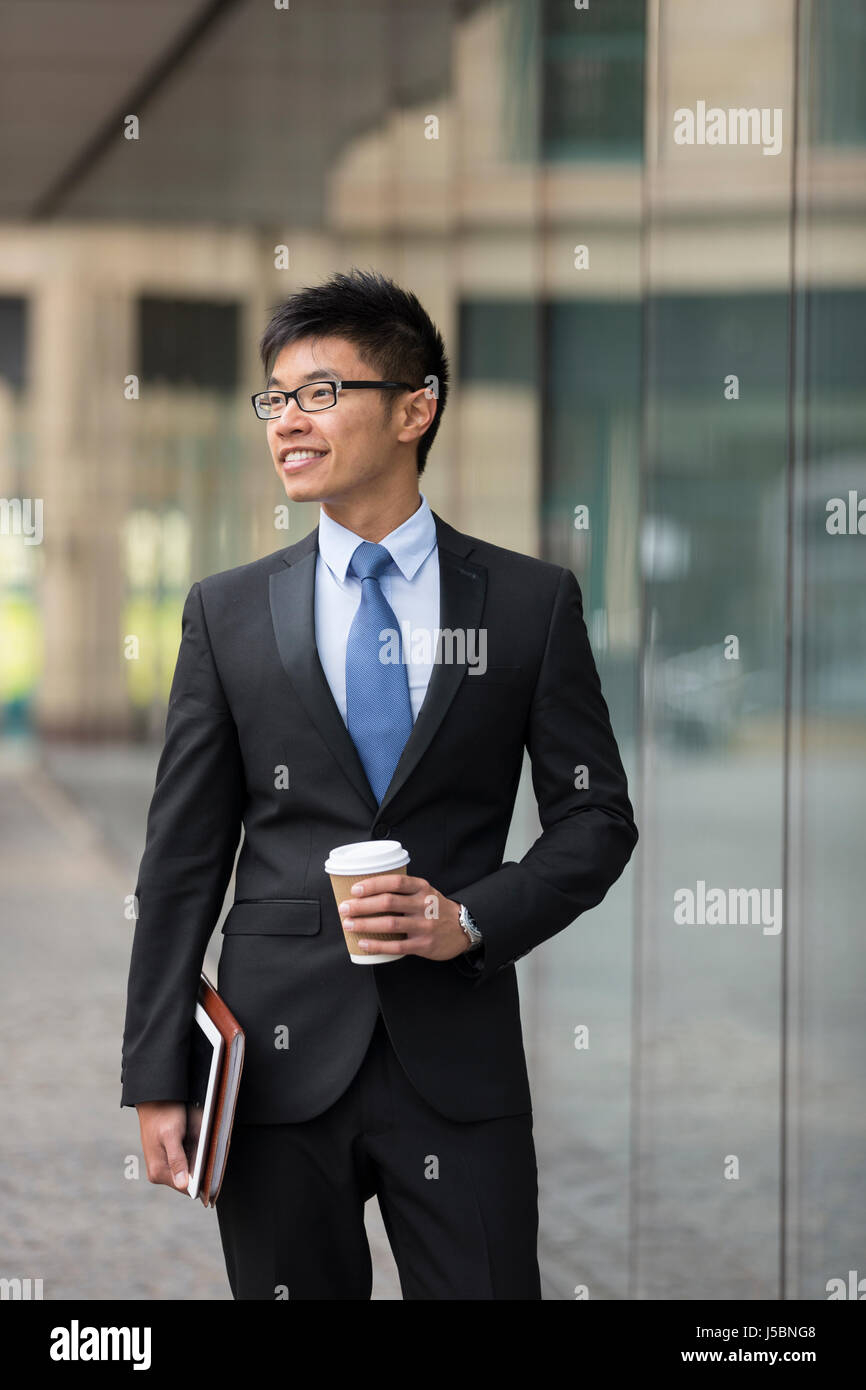 Ritratto di un imprenditore cinese al di fuori ufficio moderno edificio, guardando lontano. Foto Stock