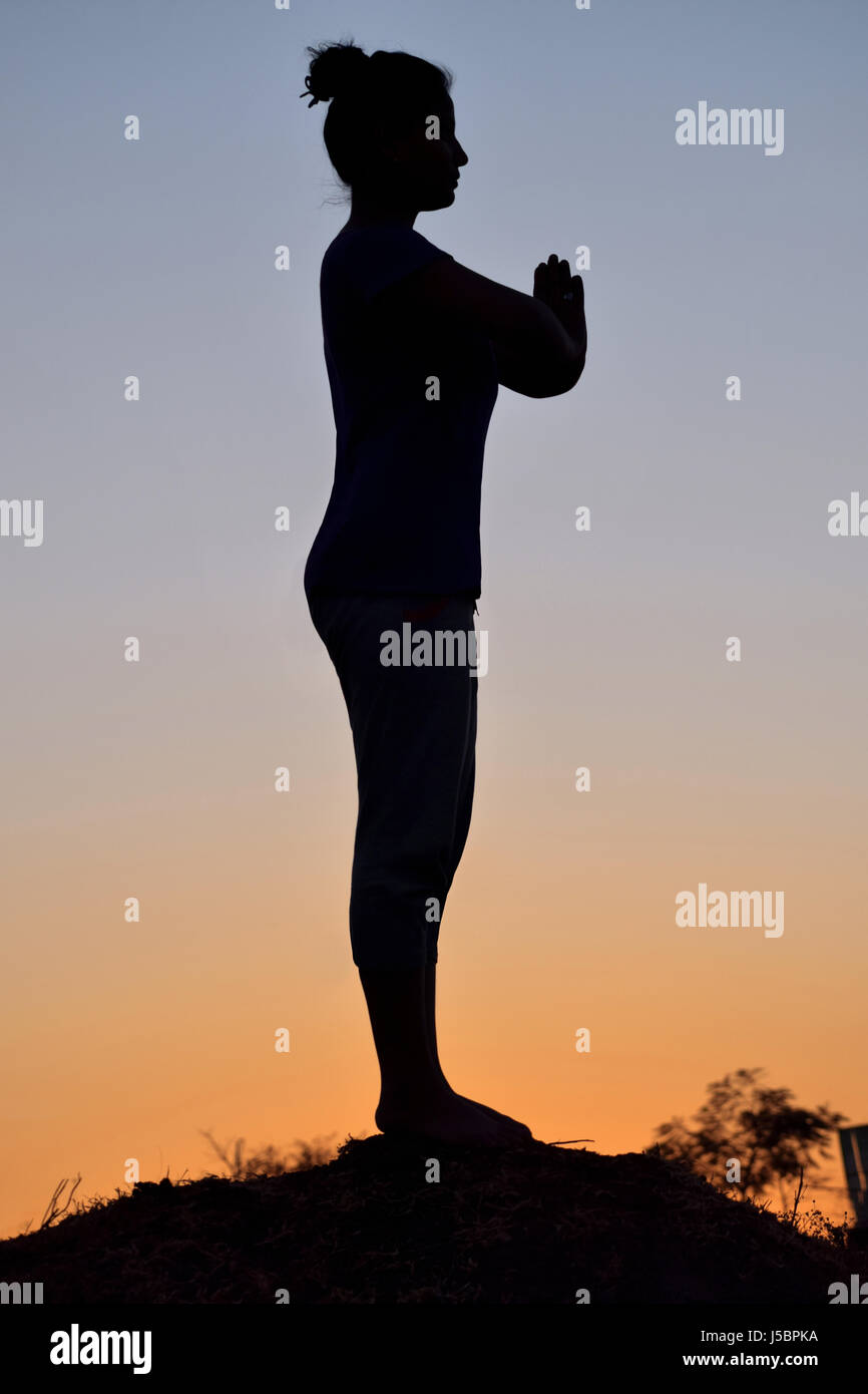 Silhouette di giovane ragazza in piedi Yoga posa, Pune, Maharashtra Foto Stock