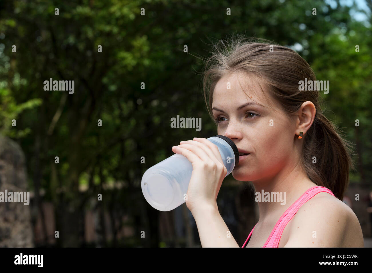 Athletic donna acqua potabile, mentre la formazione all'aperto in un ambiente naturale. Azione e uno stile di vita sano concetto. Foto Stock