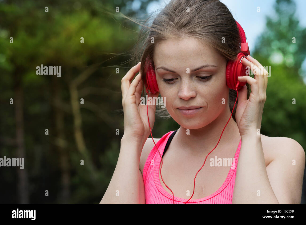Donna attivo ascoltando la sua musica su le cuffie come ella esercita al di fuori. Azione e uno stile di vita sano concetto. Foto Stock