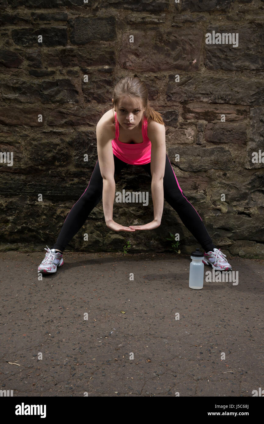 Athletic donna stretching prima o dopo la formazione. Azione e uno stile di vita sano concetto. Foto Stock