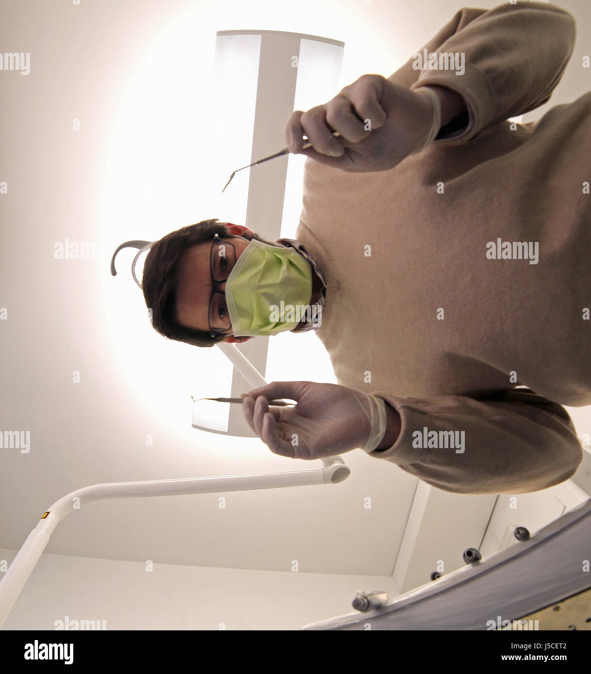 Dentista con maschera verde e dente di apparecchiature di cura nella clinica dentale Foto Stock
