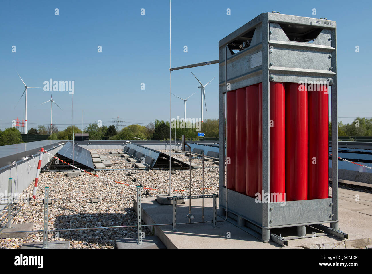 GERMANIA Amburgo, HAW Technolgy Center CC4E, Smart ENERGY, Red gas Cylinder for hydrogen storage, l'idrogeno verde H2 è stato trasformato con energia da turbine eoliche Nordex, potenza a idrogeno, unità fotovoltaica e Nordex Wind Farm Curslack / DEUTSCHLAND, Amburgo, HAW Technologiezentrum CC4E, Dach mit PV Solaranlage und Wasserstoff Speicher, Hintergrund Windpark Curslack mit Nordex N117 Windkraftanlagen Foto Stock