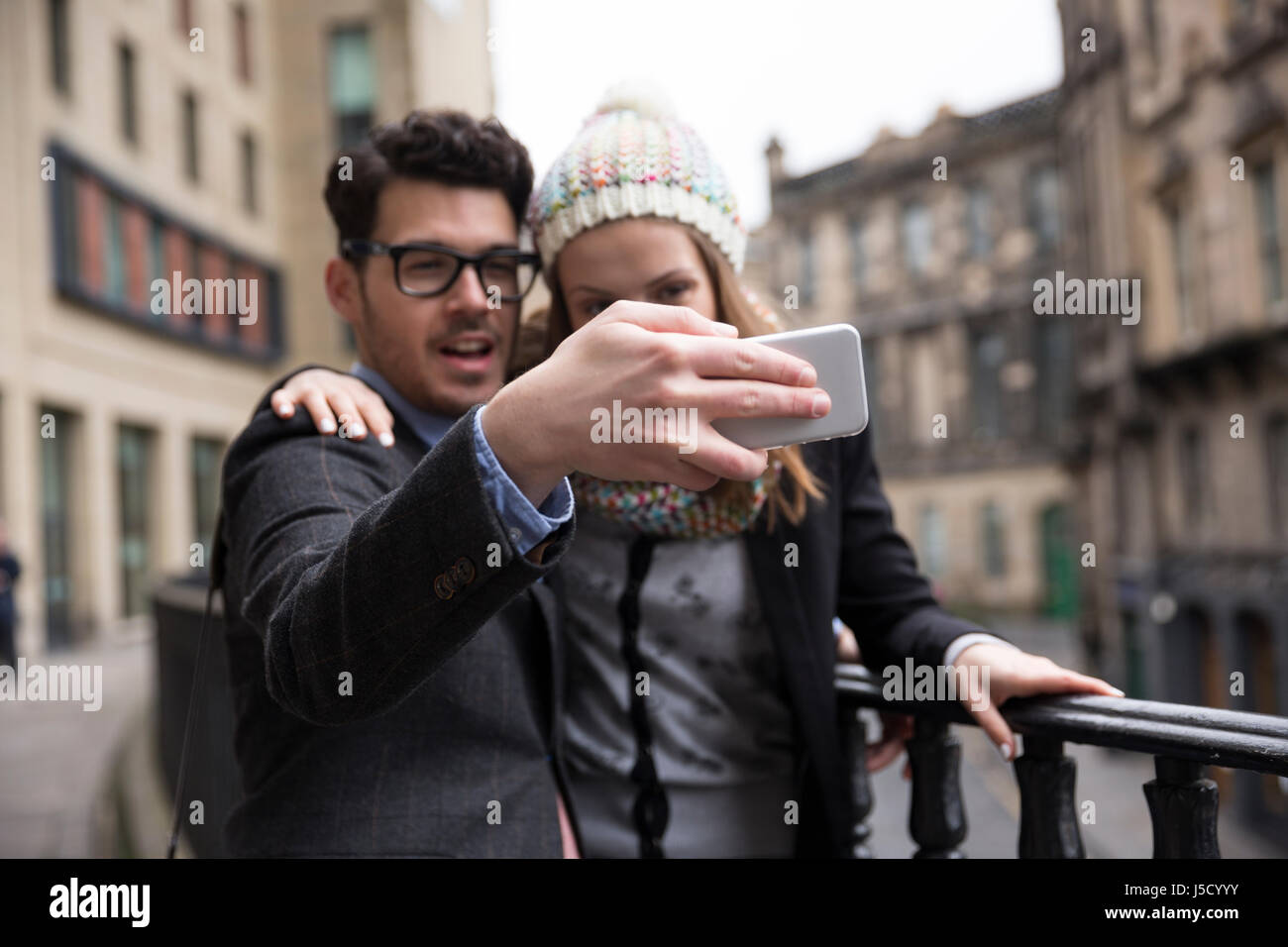La messa a fuoco è a portata di mano tenendo il telefono in primo piano. Felice coppia utilizzando un telefono intelligente per prendere un 'Selie' autoritratto. Foto Stock