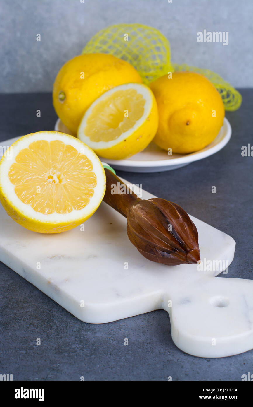 Mature succosa giallo dei limoni witn spremiagrumi stick fatto da albero di olivo legno Foto Stock