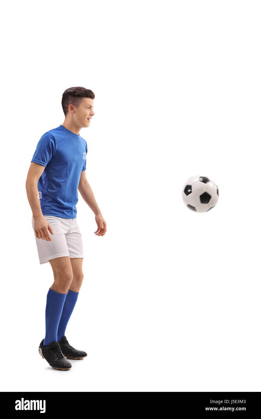 Lunghezza piena ripresa di profilo di un adolescente giocatore di calcio con un pallone da calcio isolati su sfondo bianco Foto Stock