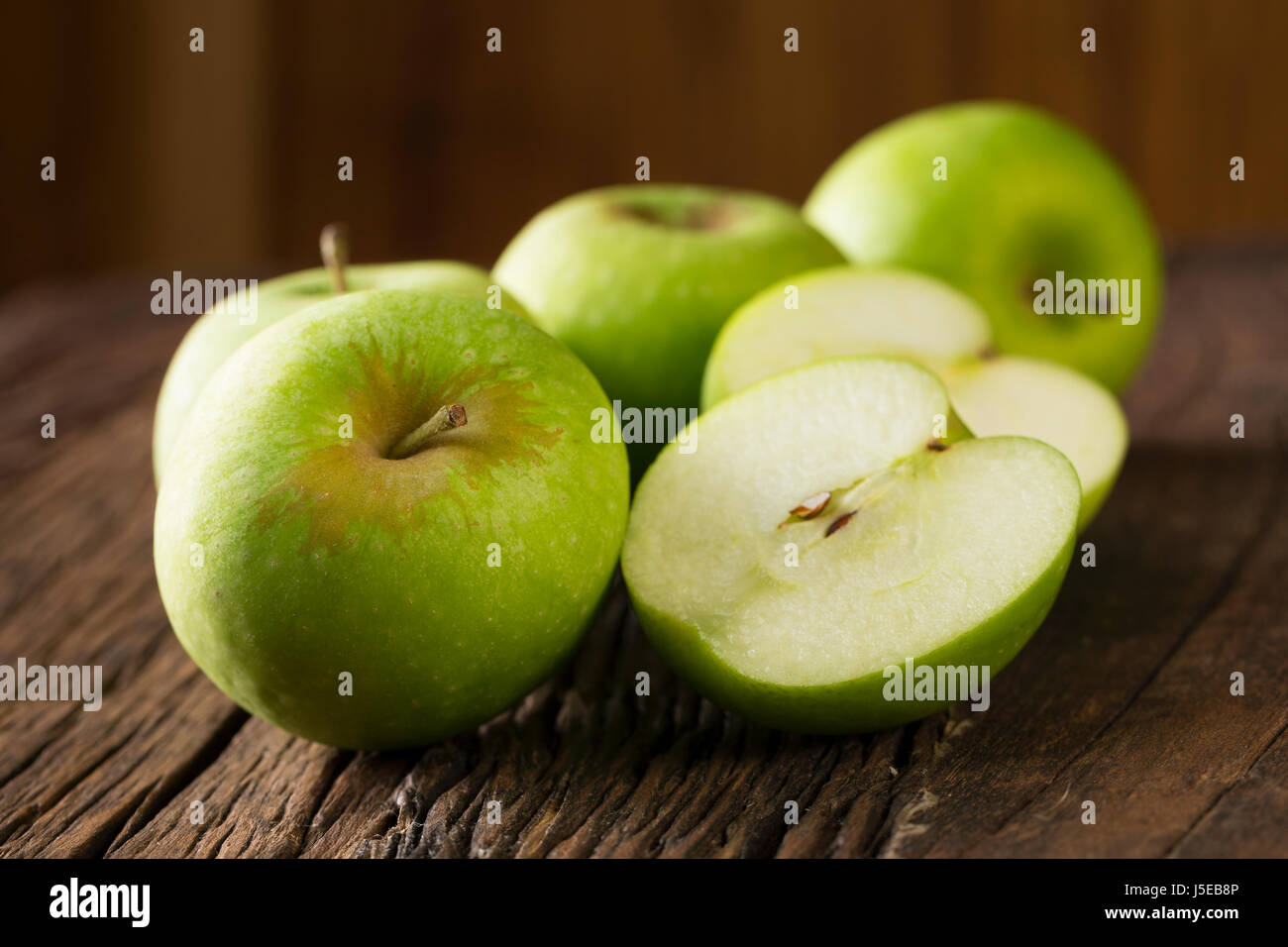 Mature mele verdi seduto su una tavola in legno rustico. Foto Stock