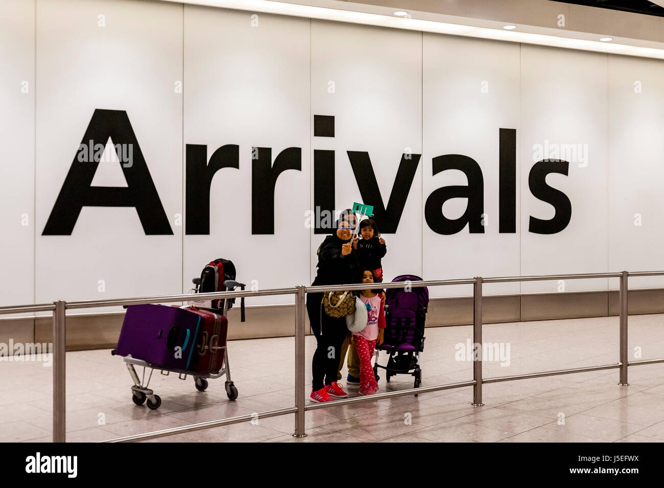 Una famiglia prendere un Selfie nella sala arrivi dell'aeroporto di Heathrow di Londra, Regno Unito Foto Stock