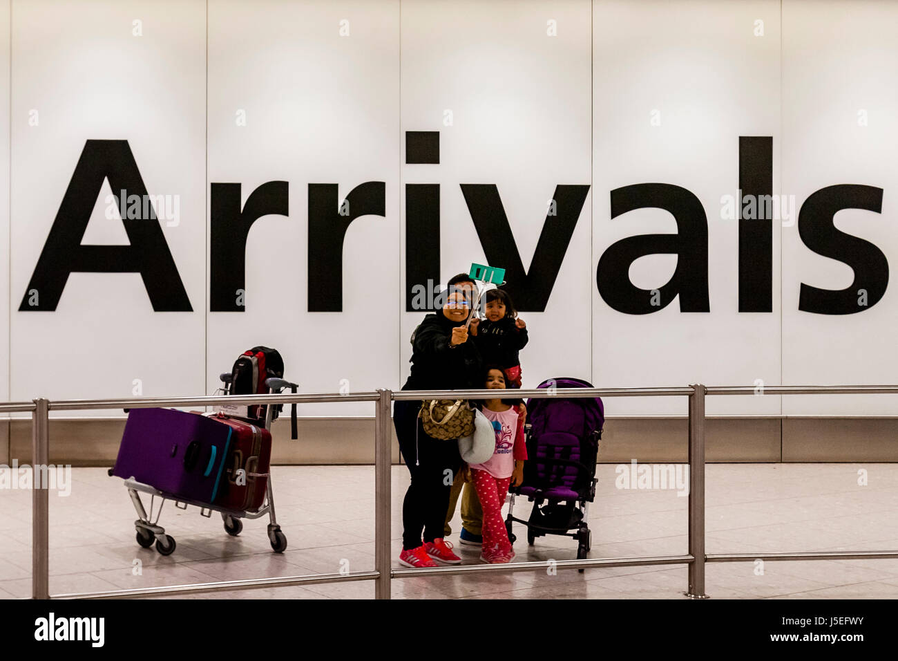 Una famiglia prendere un Selfie nella sala arrivi dell'aeroporto di Heathrow di Londra, Regno Unito Foto Stock