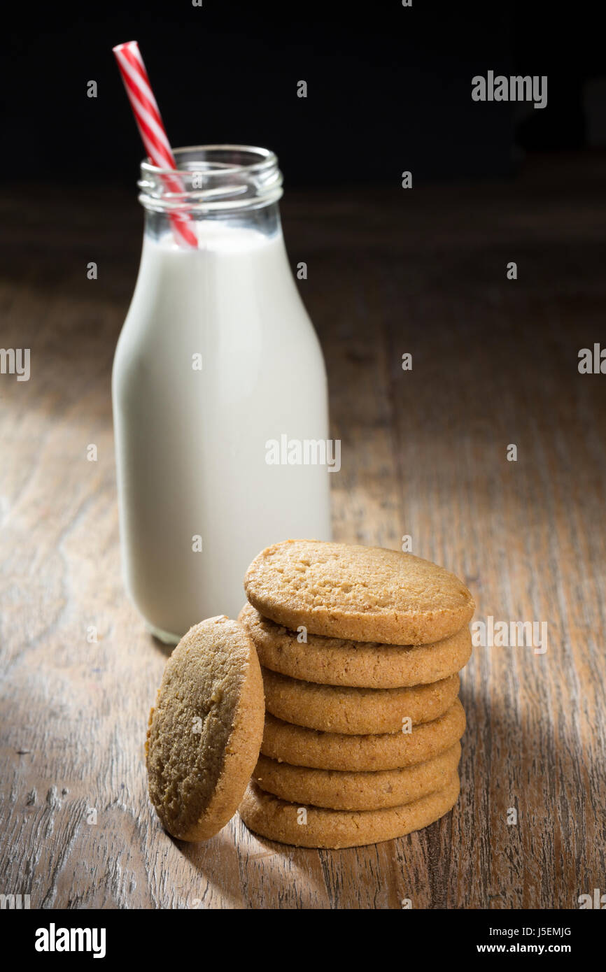 Bottiglia di latte e biscotti su una tavola in legno rustico. Foto Stock