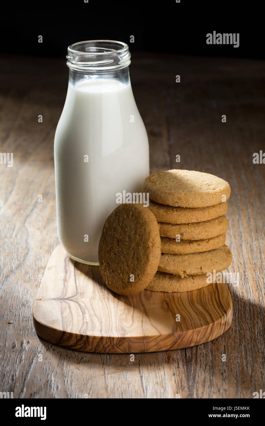 Bottiglia di latte e biscotti su una tavola in legno rustico. Foto Stock