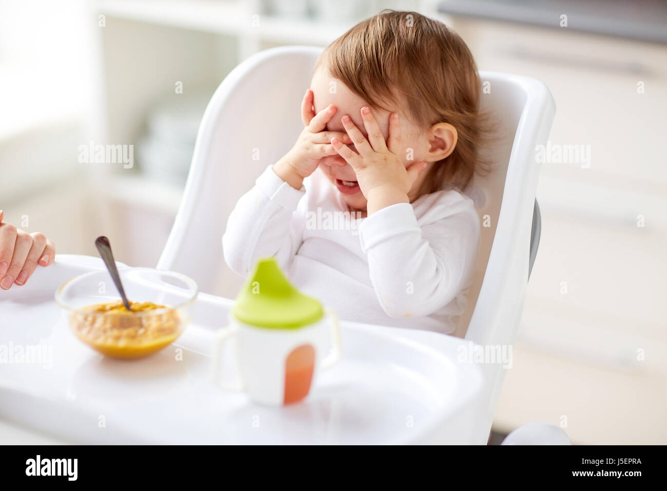 Baby sitter nel seggiolone e mangiare a casa Foto Stock