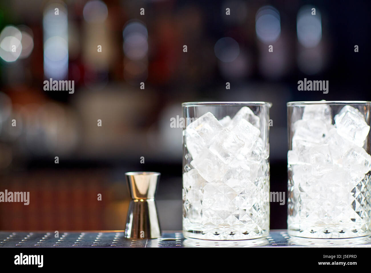 Bicchieri con ghiaccio e jigger sul bancone bar Foto Stock