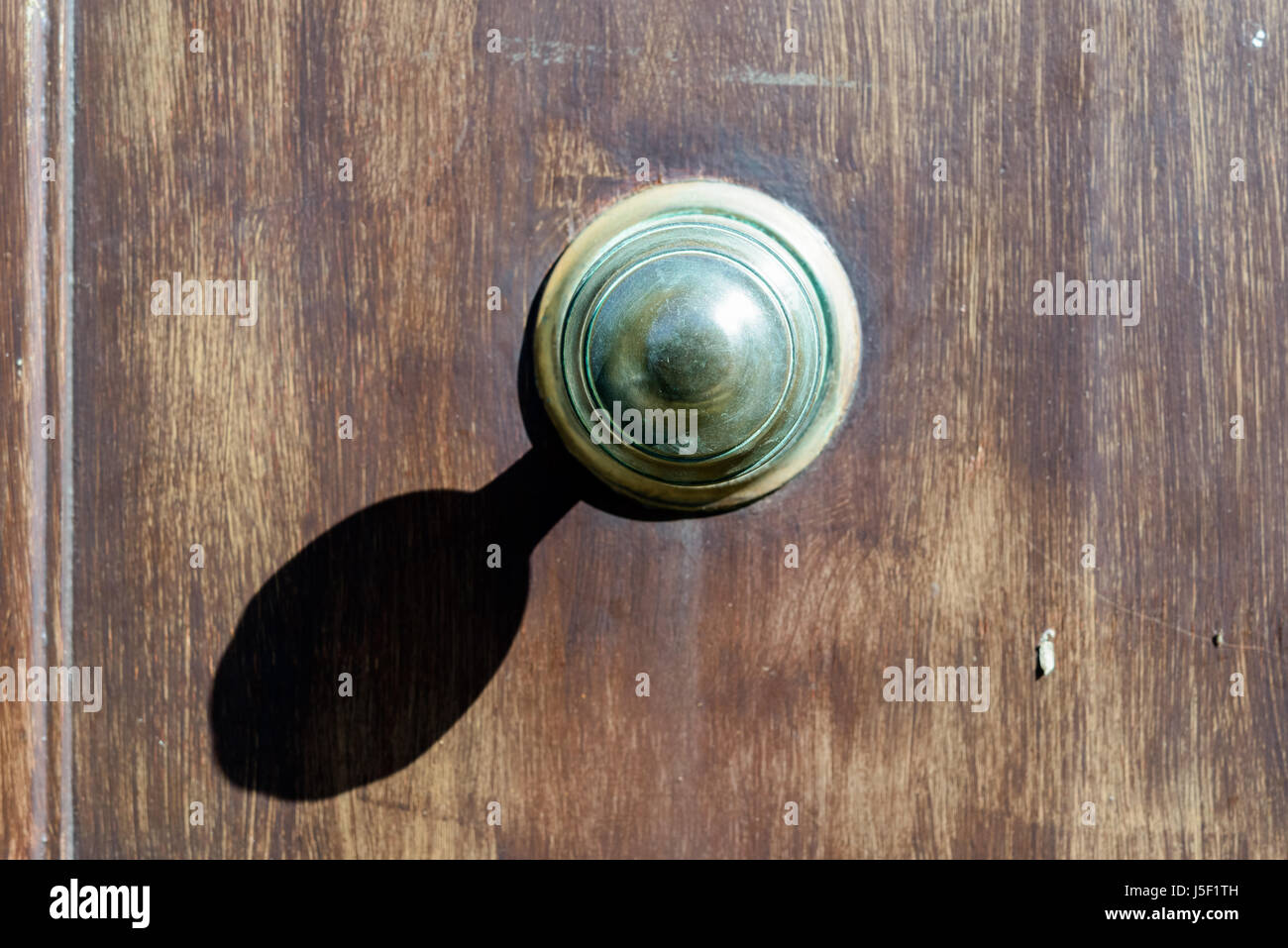 Grande manopola dello sportello la colata di una forte ombra su una porta sbiadito. Foto Stock