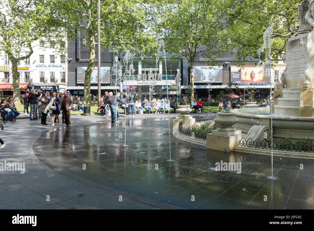 I turisti intorno alla fontana nel cuore di Leicester Square Foto Stock