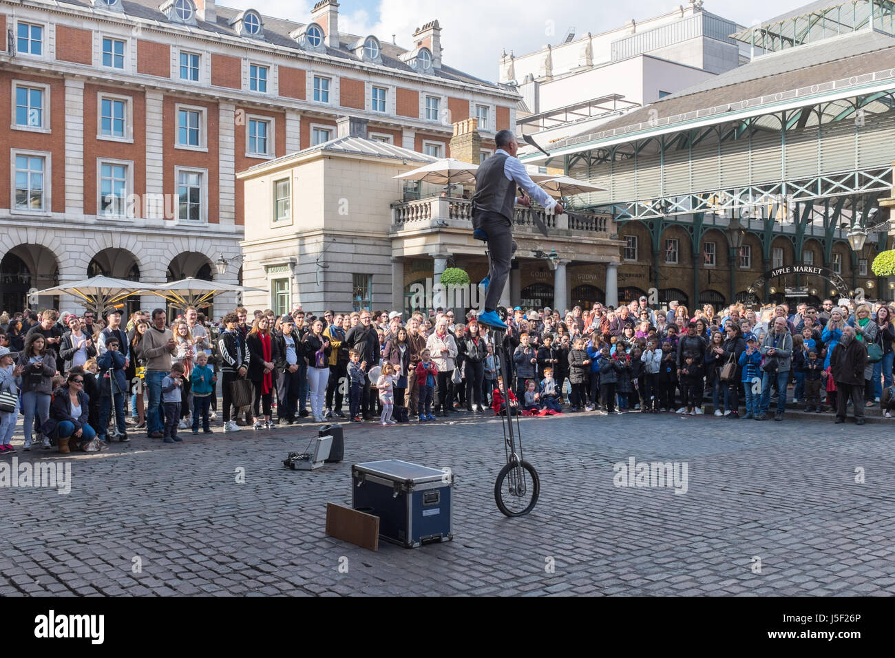 I turisti a guardare un animatore di strada nel mercato di Covent Garden di Londra Foto Stock