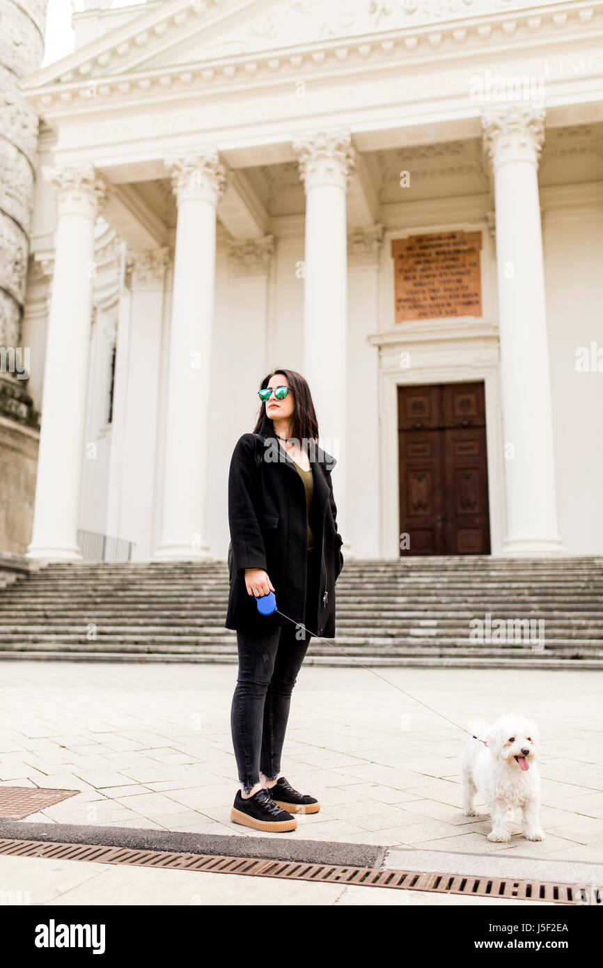 Giovane donna a piedi con un cane sulla strada Foto Stock