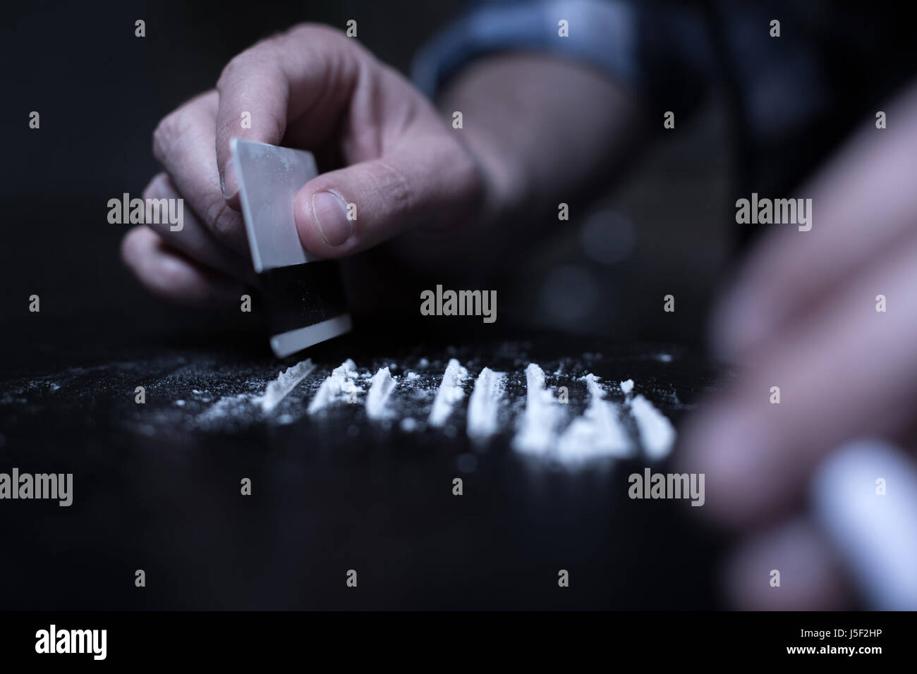 Abile Dope Addict preparando linee di cocaina nel buio Foto Stock