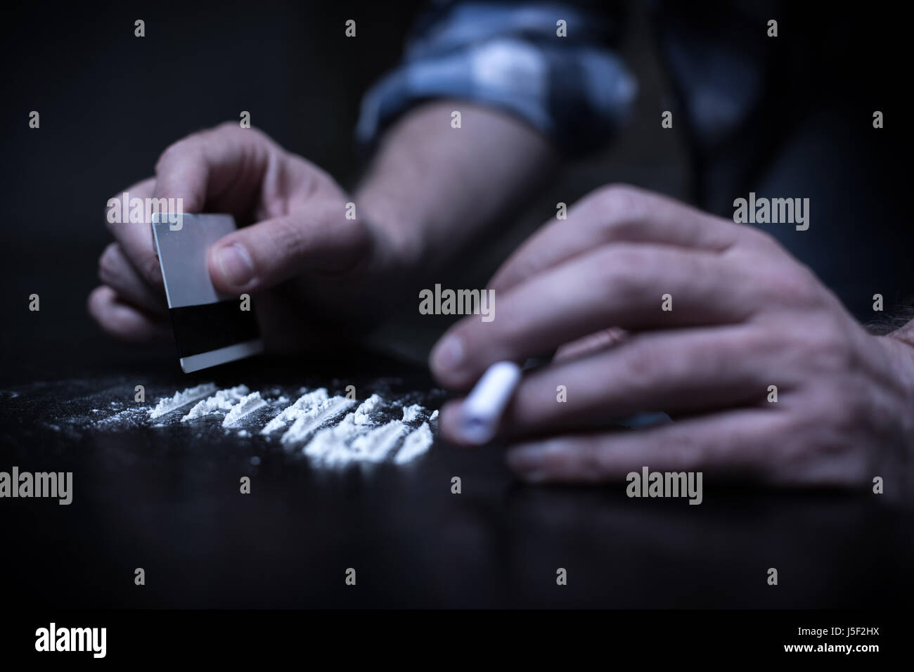 Tossicodipendenti preparando linee di eroina in luogo oscuro Foto Stock
