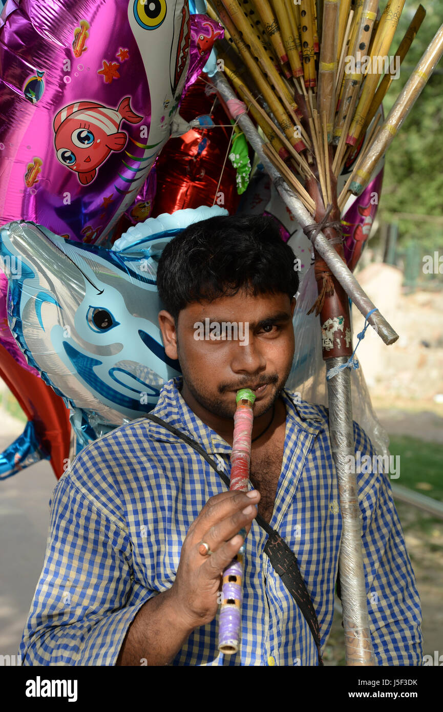 India Delhi 2017. Il Deer Park. Novità ambulante venditore di palloncino soffia un flauto Foto Stock
