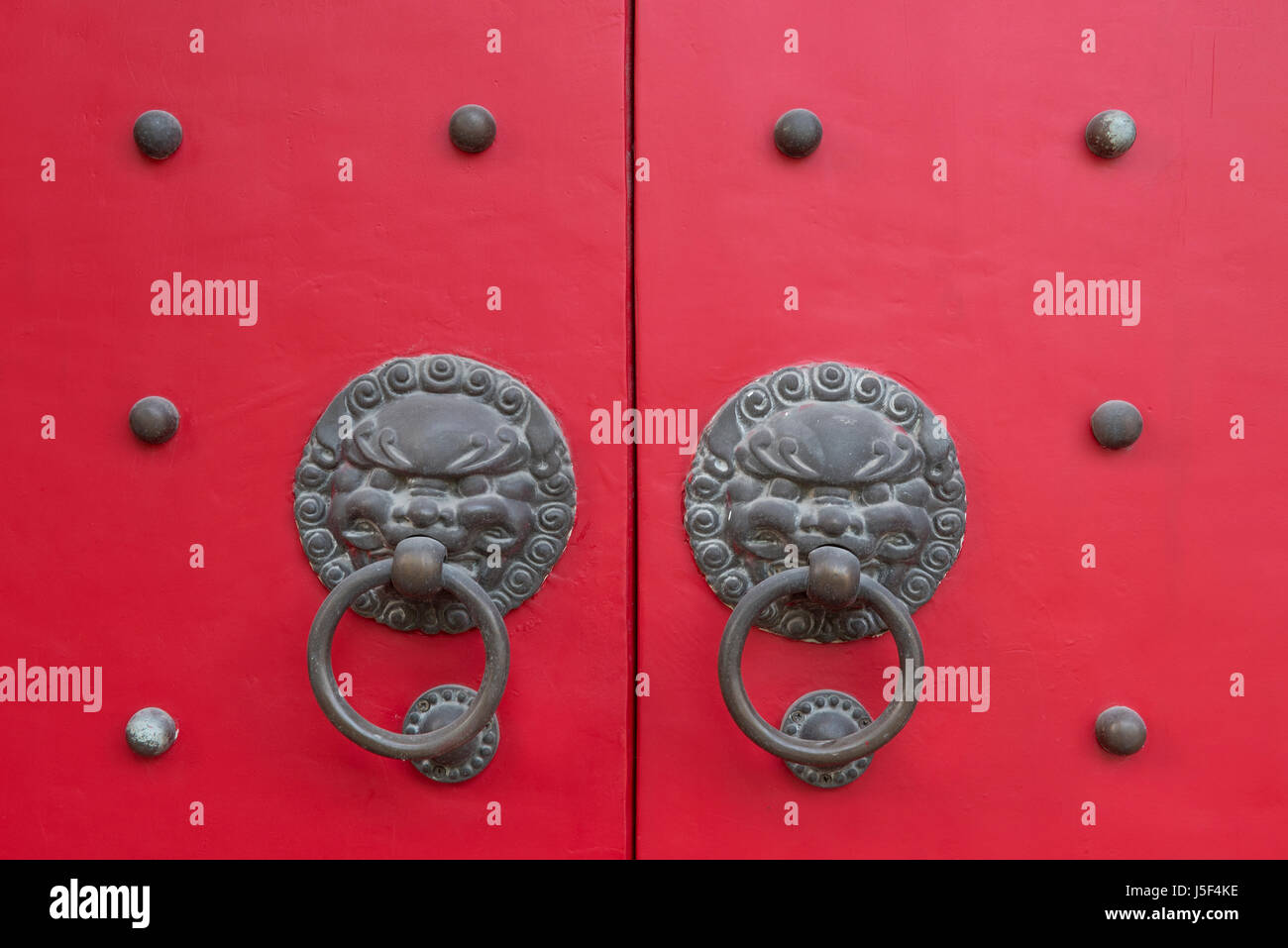 Testa leone maniglie di porte su un rosso di legno chiodati porta sulla nuvola bianca tempio buddista in Cina a Shanghai Foto Stock
