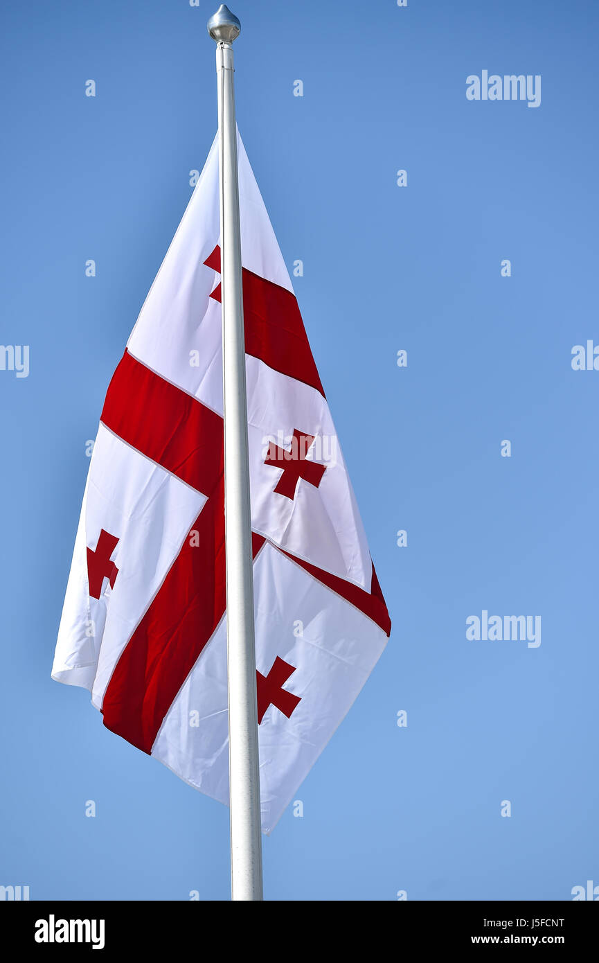 La Georgia bandiera nazionale soffiata dal vento contro un cielo blu Foto Stock