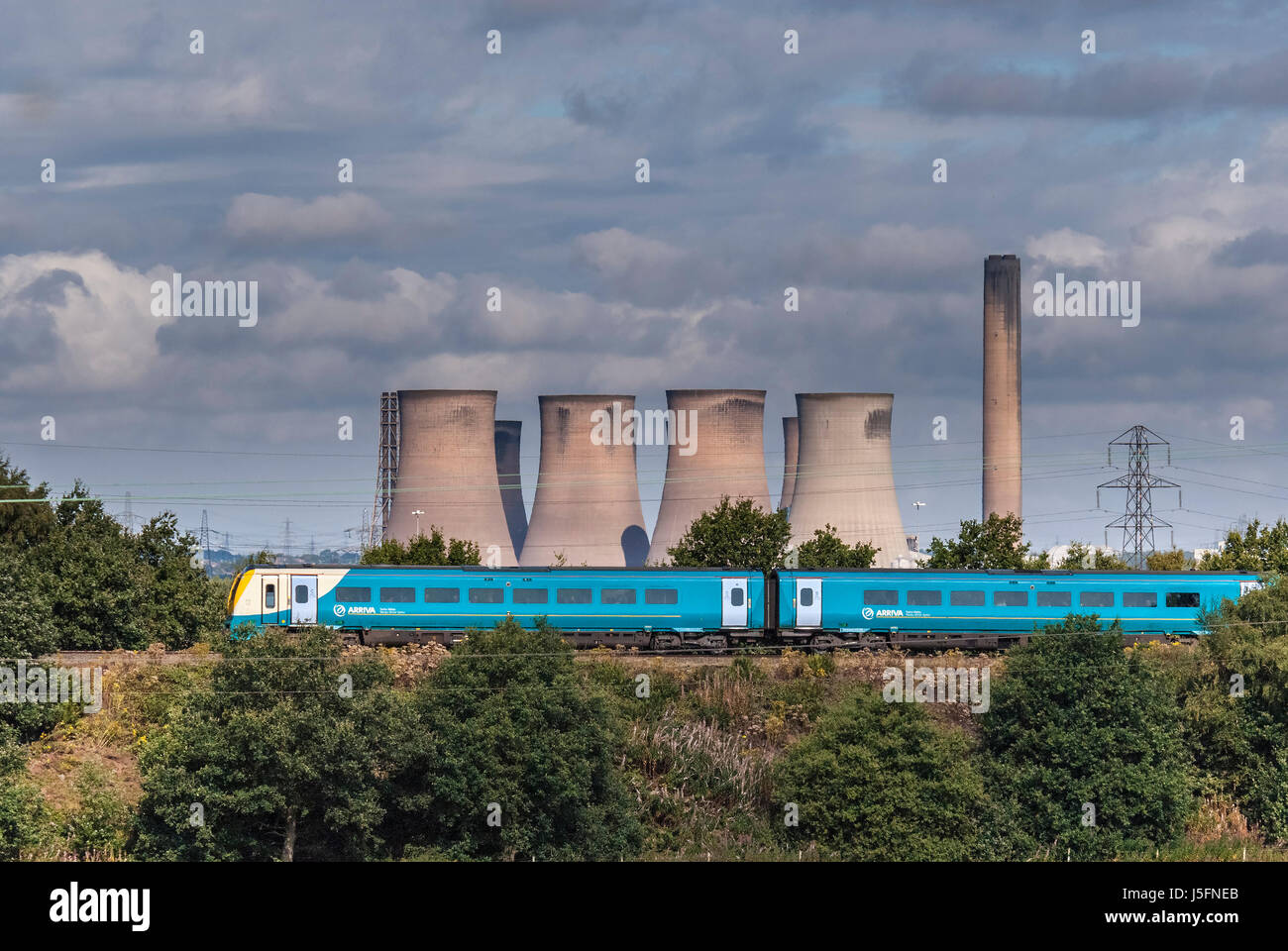 Arrivare DMU diesel treno passa Fiddlers Ferry power station. Foto Stock