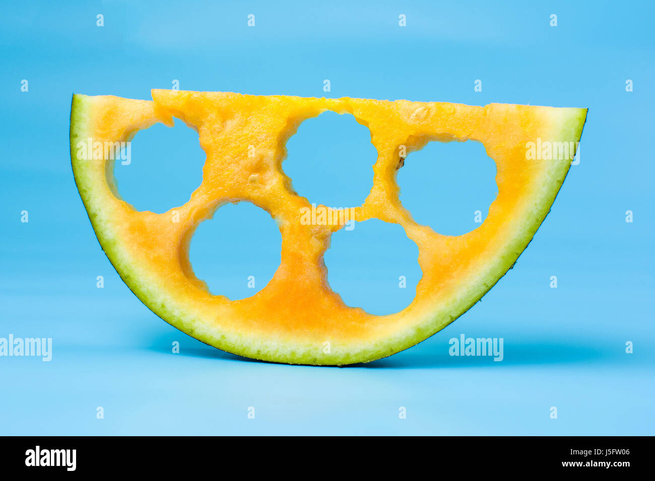 Giallo frutta anguria fetta contro sfondo blu Foto Stock
