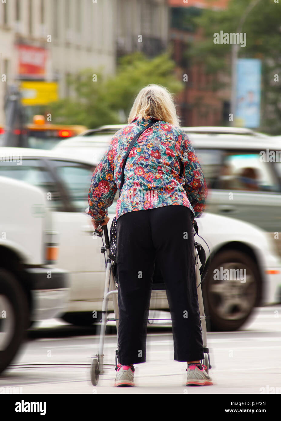 Un fragile donne anziane tentando di attraversare una affollata e trafficata strada pericolose Foto Stock