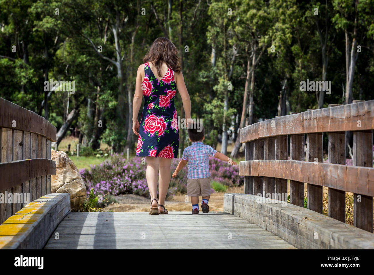 Madre e figlio attraversando un ponte di legno in una giornata di primavera. Foto Stock