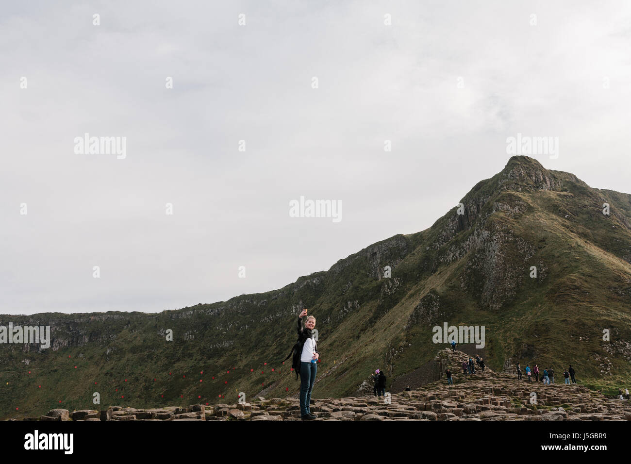 Turista femminile prendendo un selfie inil Giant's Causeway. Foto Stock