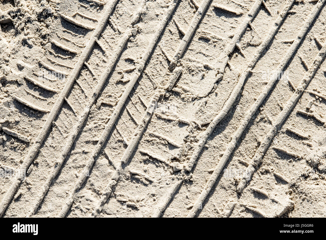 In un pneumatico di un veicolo le vie nella sabbia. La guida è consentita sulla spiaggia di Port Aransas, Texas USA, lasciando tracce della giornata di attività. Foto Stock