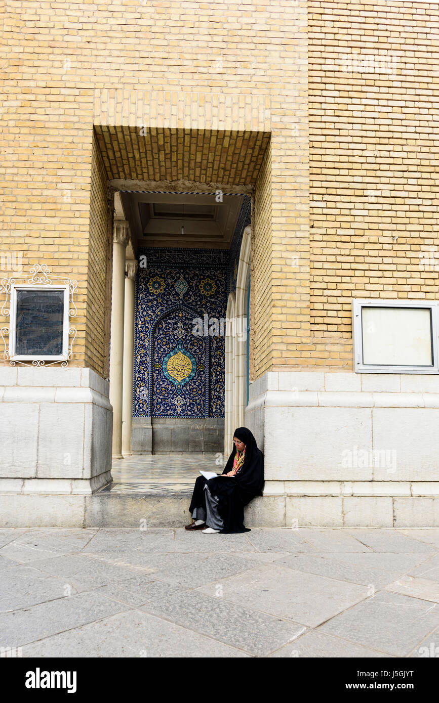 Musulmano persiano donna seduta sul pavimento sotto la moschea arch in Iran Foto Stock