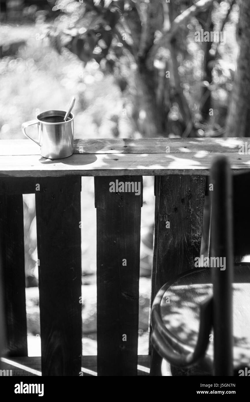 Boccale di metallo e una sedia su una terrazza in legno. Foto in bianco e nero Foto Stock