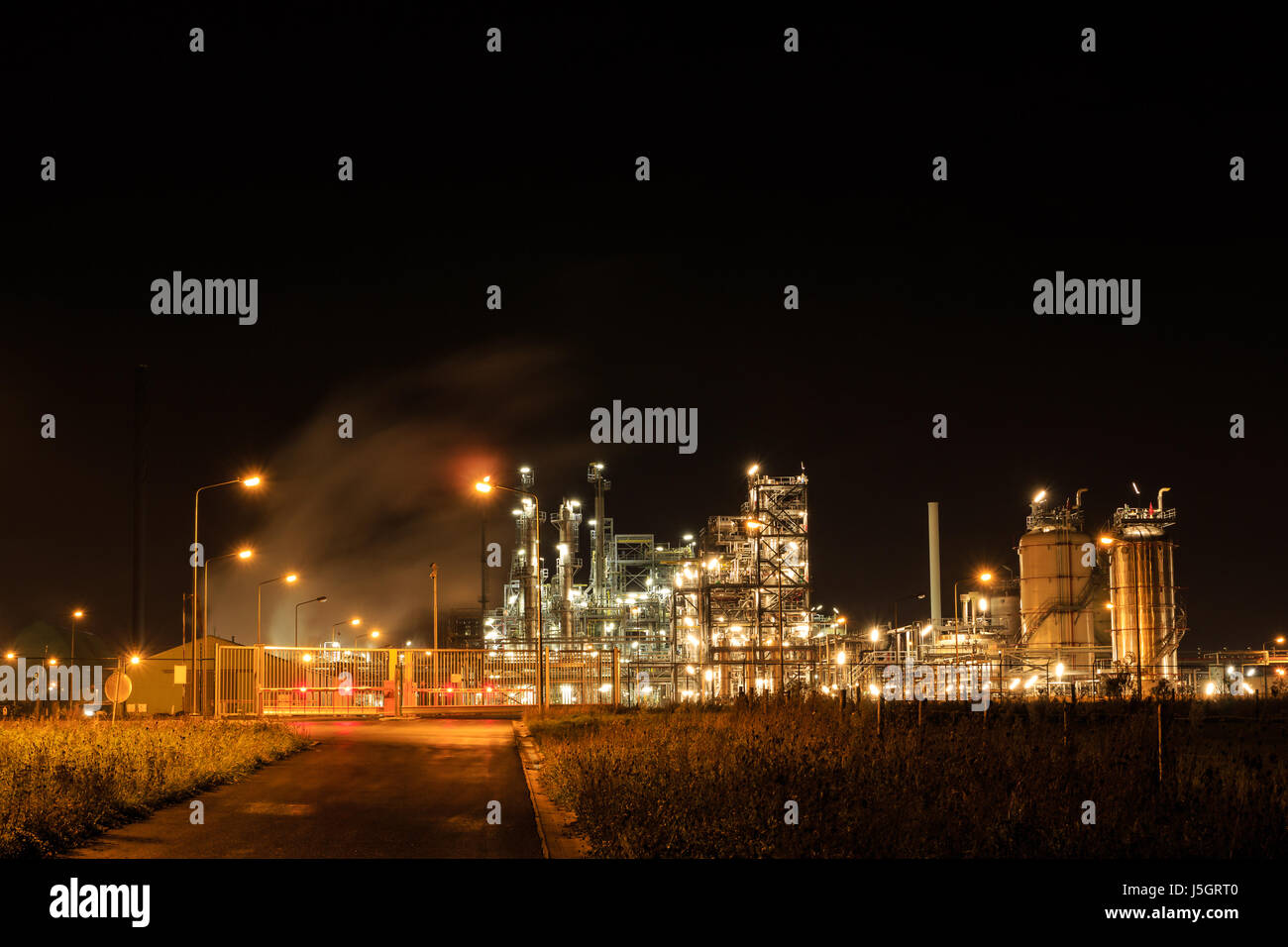 Raffineria petrolchimica di notte dietro un recinto chiuso. Tessenderlo, Fiandre, in Belgio, Europa Foto Stock